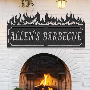 Puede incluir: Letrero metálico negro con el texto "ALLEN'S BARBECUE" sobre una chimenea de ladrillo. El letrero tiene un diseño de llamas. La escena incluye sillas de mimbre, faroles y una pequeña mesa, creando un ambiente de comedor al aire libre.