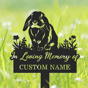 Könnte beinhalten: Schwarzer Metall-Gartenstecker mit einer Silhouette eines Kaninchens mit langen Ohren, das inmitten stilisierter Blumen und Blätter sitzt. Das Schild trägt die Aufschrift "In Loving Memory of" über einem Feld für einen individuellen Namen.