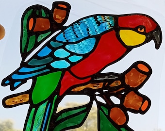 Könnte beinhalten: Ein Buntglas-Fensterbild mit einem roten, blauen und grünen Vogel, der auf einem Ast mit braunen und orangefarbenen Gummikernen sitzt. Der Vogel hat einen gelben Schnabel und schwarze Augen.
