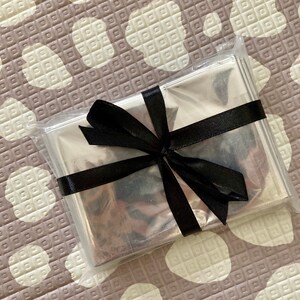 May include: A silver emergency blanket wrapped in a clear plastic bag with a black ribbon tied in a bow.