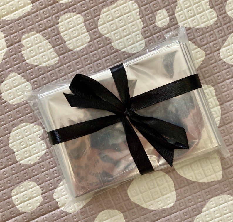 May include: A silver emergency blanket wrapped in a clear plastic bag with a black ribbon tied in a bow.