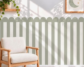May include: A wall covering featuring vertical sage green and white stripes with a scalloped top edge. The wallpaper pattern is applied to a wall behind a light-colored armchair, a wooden shelf with a green plant, and a framed moon and star print.