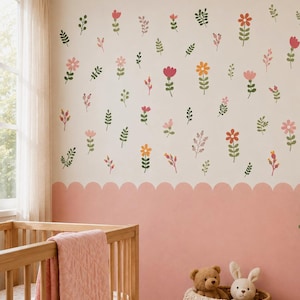 May include: A wall decal set featuring various small, colorful flowers and green leafy sprigs scattered across a cream-colored wall. The lower portion of the wall is painted a solid, muted pink with a scalloped edge border design.