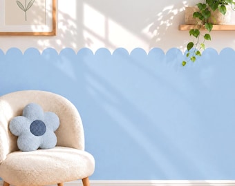 May include: A light blue scalloped wall decal applied to the lower half of a wall, featuring a rounded edge design. The wall is decorated with a framed print of a blue flower and a potted trailing green plant on a wooden shelf above the decal.