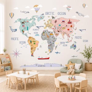 May include: A large wall decal featuring a colorful world map with labeled continents and oceans. The map includes illustrations of animals, landmarks, airplanes, and hot air balloons. The design is printed in soft pastel tones on a white background.