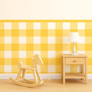 May include: A light wood rocking horse and a small wooden nightstand with a lamp are set against a yellow and white checkered wall. The lamp has a white shade and a white base. The room has a light wood floor.