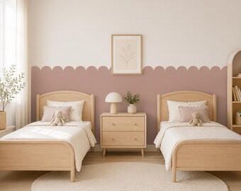 May include: Two light wood twin beds with white bedding, each featuring a small plush toy. Between the beds sits a light wood two-drawer nightstand with a mushroom-shaped lamp and a small potted plant. The wall has a scalloped dusty rose paint design.
