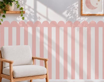 May include: A wall mural featuring vertical stripes in alternating shades of soft pink and white, topped with a scalloped edge border. The design covers the wall behind a light-colored upholstered armchair with wooden armrests and legs.