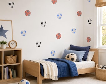 May include: A set of wall decals featuring multiple soccer balls in various colors including black and white, blue and white, and red and white patterns. The decals are arranged across a plain white wall above a wooden bed frame with blue bedding.