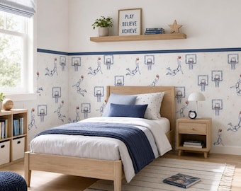 May include: A light wood bed frame with a white comforter and a navy blue throw blanket. The room features wallpaper with basketball player illustrations and hoops, a wooden nightstand, and a shelf with a sign reading PLAY BELIEVE ACHIEVE.