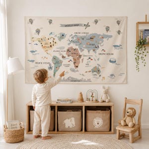 May include: A fabric wall hanging featuring a world map with muted colours, illustrations of animals, and the text WORLD MAP. The map displays continents, oceans, and various geographical labels, accented by small drawings of hot air balloons.
