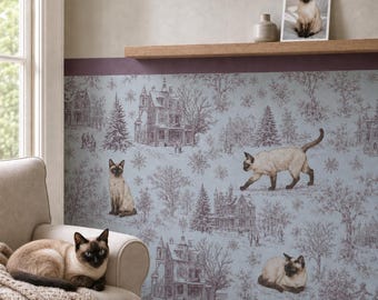 May include: A light blue wallpaper featuring a dark brown toile pattern of winter houses, trees, and snowflakes, with three Siamese cats integrated into the design and one live Siamese cat resting on a beige armchair in the foreground.