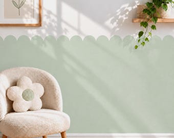 May include: A light green scalloped wall decal applied to the lower half of a wall, featuring a soft matte finish. The wall is decorated with a framed floral print and a trailing green plant on a wooden shelf, with a cream-colored flower pillow.