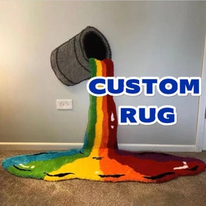 May include: A custom rainbow rug shaped like a paint bucket pouring out paint. The rug is made of fluffy yarn and has a gray paint bucket at the top. The text "CUSTOM RUG" is written in blue letters on the wall.