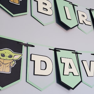 May include: A black and green banner with the words "Birthday" and "David" in white letters. The banner also features a green character with large eyes and a brown coat.