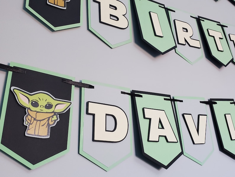 May include: A black and green banner with the words "Birthday" and "David" in white letters. The banner also features a green character with large eyes and a brown coat.