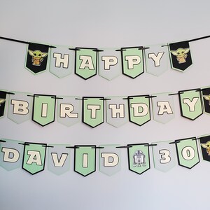 May include: A green and white banner with black string, featuring the words "Happy Birthday David 30". The banner has images of a cartoon character, a robot, and a star.