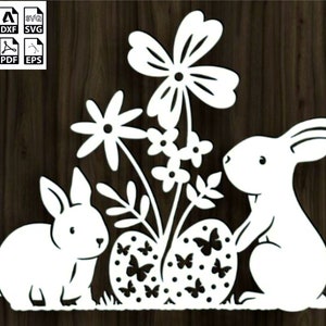 May include: White silhouette of two bunnies with a flower arrangement and two Easter eggs. The bunnies are facing each other, one is looking at the eggs and the other is looking at the flowers. The flowers are in a vase and have a variety of shapes and sizes. The eggs are decorated with butterflies.