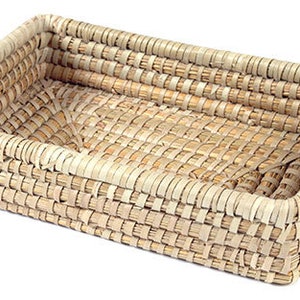 Puede incluir: Una cesta rectangular tejida de materiales naturales. La cesta tiene un color marrón claro y un patrón tejido. Es ideal para guardar objetos pequeños.