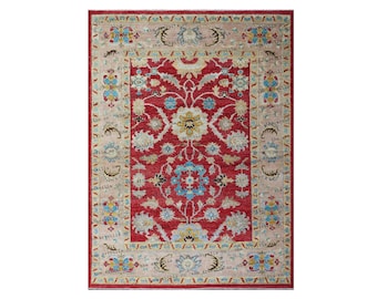 May include: A red rug with a floral pattern in shades of blue, yellow, and white. The rug has a border with a repeating pattern of small flowers and leaves.
