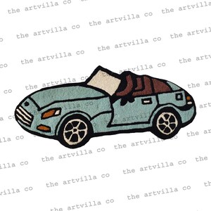 Puede incluir: Una alfombra de coche convertible azul claro con asientos marrones y ruedas negras. La alfombra está hecha de un material suave y mullido y es perfecta para añadir un toque de fantasía a cualquier habitación.