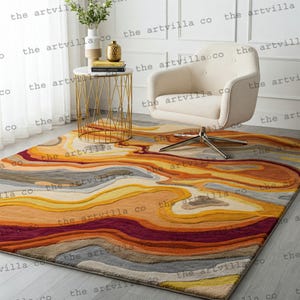 May include: A rectangular rug with an abstract design in shades of yellow, orange, red, and grey. The rug features a swirling, layered pattern, creating a modern look. The rug is placed on a light-coloured floor. The rug's design resembles a landscape.