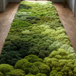 May include: A rectangular rug with a dense, textured surface, displaying a gradient of green shades. The rug's design resembles a natural mossy landscape, creating a soft, organic aesthetic. The rug is placed on a wooden floor.