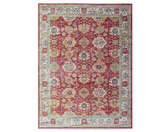 May include: A red, cream, and blue patterned rug with a floral design. The rug has a border with a repeating pattern.