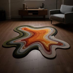 May include: An abstract rug with a fluid, organic form. The rug showcases a layered design with shades of orange, brown, green, and grey. It is placed on a wooden floor, enhancing the room's warmth. The rug's design evokes a melting shape, adding a modern touch.