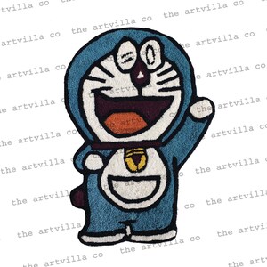 May include: A blue and white plush rug featuring a cartoon character with a large smile and a blue collar. The character has a white face with black eyes and a red mouth.