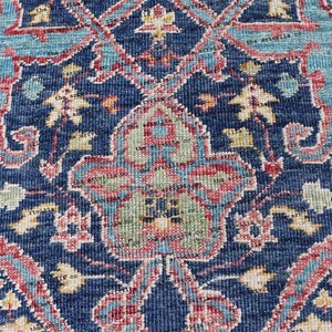 May include: Close-up of a blue rug with a floral pattern. The rug has a detailed design with intricate details in shades of pink, blue, and yellow.