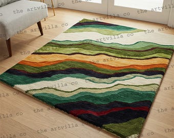 May include: A rectangular area rug with a landscape design. The rug features horizontal bands of color, including green, orange, and cream. The rug is placed on a hardwood floor.