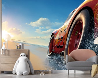 May include: A red race car with the number 95 on the side drives through a spray of water on a beach. The car is driving towards the viewer and the sun is shining in the background.