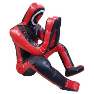 May include: A red and black padded training dummy in a seated position with arms crossed. The dummy is made of durable material and is designed for martial arts training.
