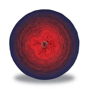 May include: A round ball of yarn with a gradient of colors, transitioning from deep blue to red. A small gold-colored heart charm is attached to the yarn. The yarn is likely for knitting or crocheting projects.