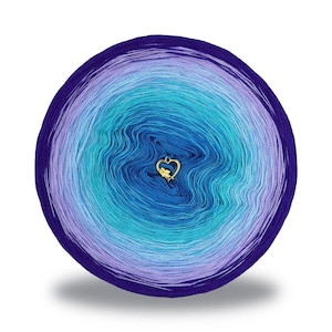 Puede incluir: Una bola redonda de hilo en tonos de azul, turquesa y morado. Un pequeño dije dorado en forma de corazón está sujeto al centro del hilo. El hilo está enrollado firmemente, creando un efecto degradado desde el borde exterior oscuro hasta el centro más claro.
