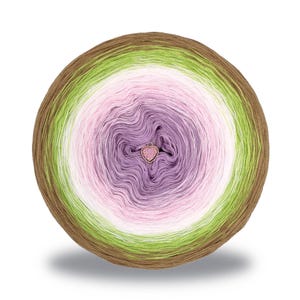 Op de afbeelding: Een ronde bol garen in bruin, groen, wit, roze en paars. Een kleine, hartvormige bedel is in het midden bevestigd. Het garen is in concentrische cirkels gerangschikt, waardoor een gradiënteffect ontstaat. Ideaal voor brei- en haakprojecten.