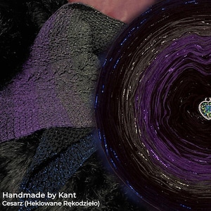 Puede incluir: Primer plano de un ovillo de hilo en tonos negros, morados y plateados, con una pieza de punto en la misma combinación de colores. El hilo está etiquetado como "Handmade by Kant" y "Cesarz (Heklowane Rękodzieło)". Un dije en forma de corazón está adjunto al hilo.