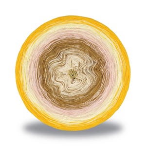 May include: A round skein of yarn in a gradient of colors, including yellow, cream, pink, and brown. A small gold-colored heart-shaped charm is attached to the center of the yarn. The yarn is likely for knitting or crocheting projects.