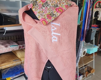 Op de afbeelding: Een roze badjas met een bloemenprint tasje erop. De badjas heeft de naam "Isla" geborduurd.