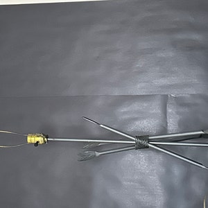 May include: A metal arrow display with multiple arrows fanned out from a central point. The arrows have a silver finish and are bound together with wire. The display includes a circular base and a gold-colored component.