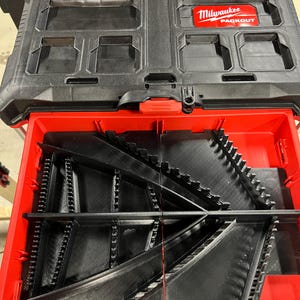 May include: Black and red Milwaukee Packout tool box with an open drawer. The top section is black with storage compartments. The drawer is red and contains black dividers. The Milwaukee Packout logo is visible.