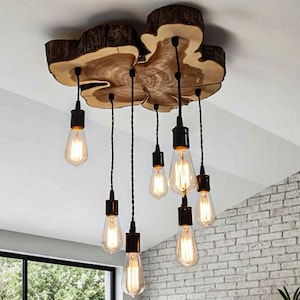 Peut inclure: Un lustre rustique en bois avec sept ampoules de style Edison suspendues au-dessus d'une table à manger grise. Le luminaire est fait d'une dalle de bois naturel. La salle à manger dispose d'une grande fenêtre et d'un mur en briques.