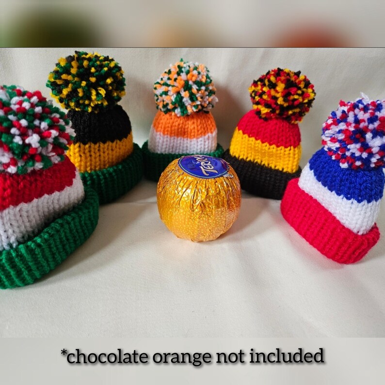 May include: Four knitted hats with pom-poms in different color combinations, including red, white, green, black, yellow, and blue. A gold chocolate orange is in the center of the image. *chocolate orange not included*