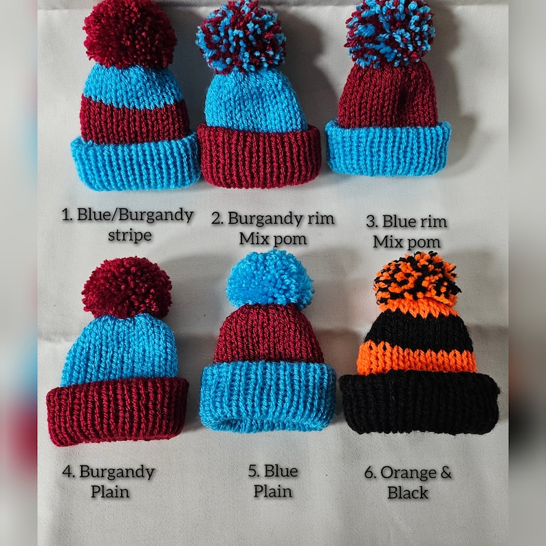 May include: Six knitted hats with pom-poms in various color combinations. The hats are blue, burgundy, black, and orange. The pom-poms are also in various colors, including blue, burgundy, orange, and black. The hats are numbered 1 through 6, with a description of each hat's color combination below it.