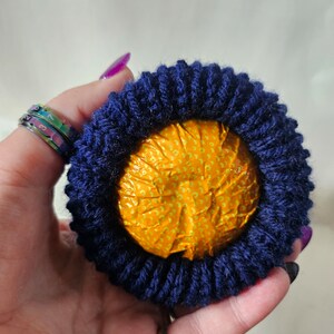 May include: A round, yellow, patterned object wrapped in a dark blue knitted fabric.