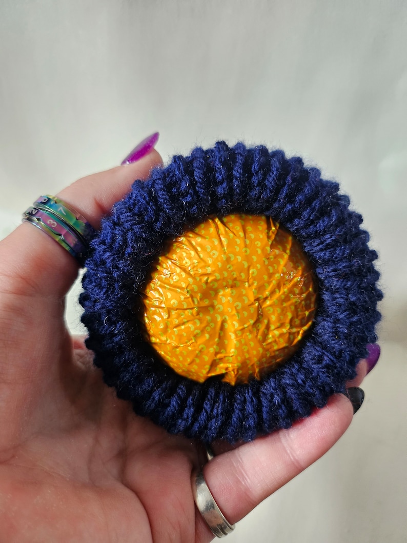 May include: A round, yellow, patterned object wrapped in a dark blue knitted fabric.