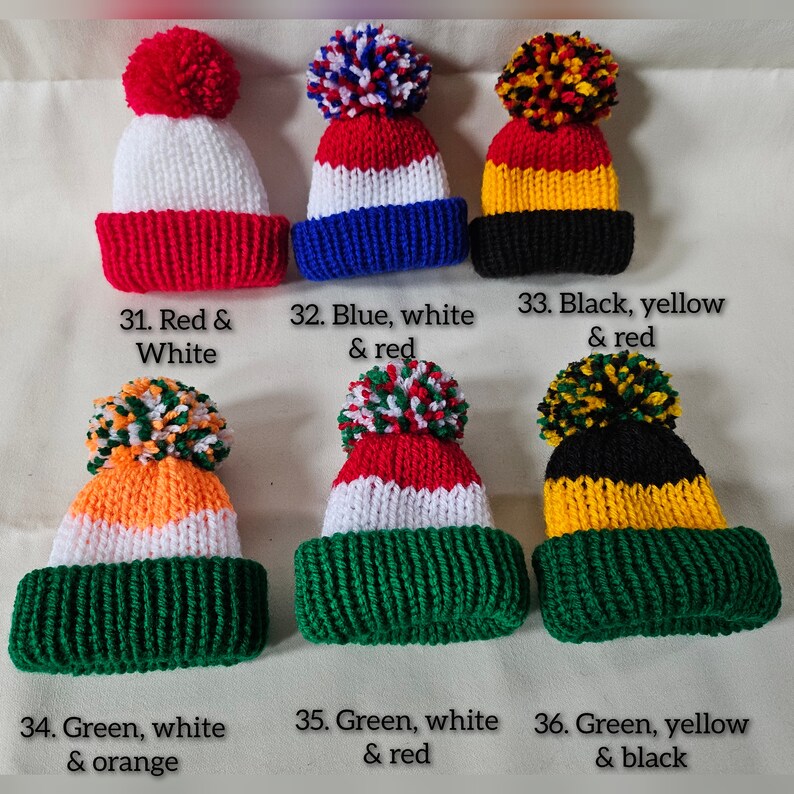 May include: Six knitted hats with pom-poms in various color combinations. The hats are red and white, blue and white, black and yellow, green and white, green and red, and green and black.
