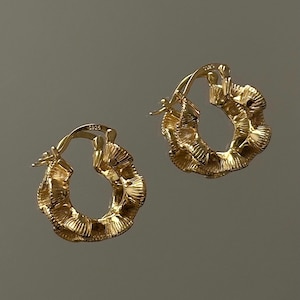 Pode incluir: Um par de brincos de argola de ouro com um design texturizado e franzido. Os brincos têm um diâmetro de aproximadamente 2,5 cm.