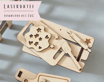 May include: A set of wooden cookie cutters for making gingerbread cookies. The cutters are shaped like a gingerbread man, a rolling pin, a spatula, and a star. The cutters are made of natural wood and have a rustic look.